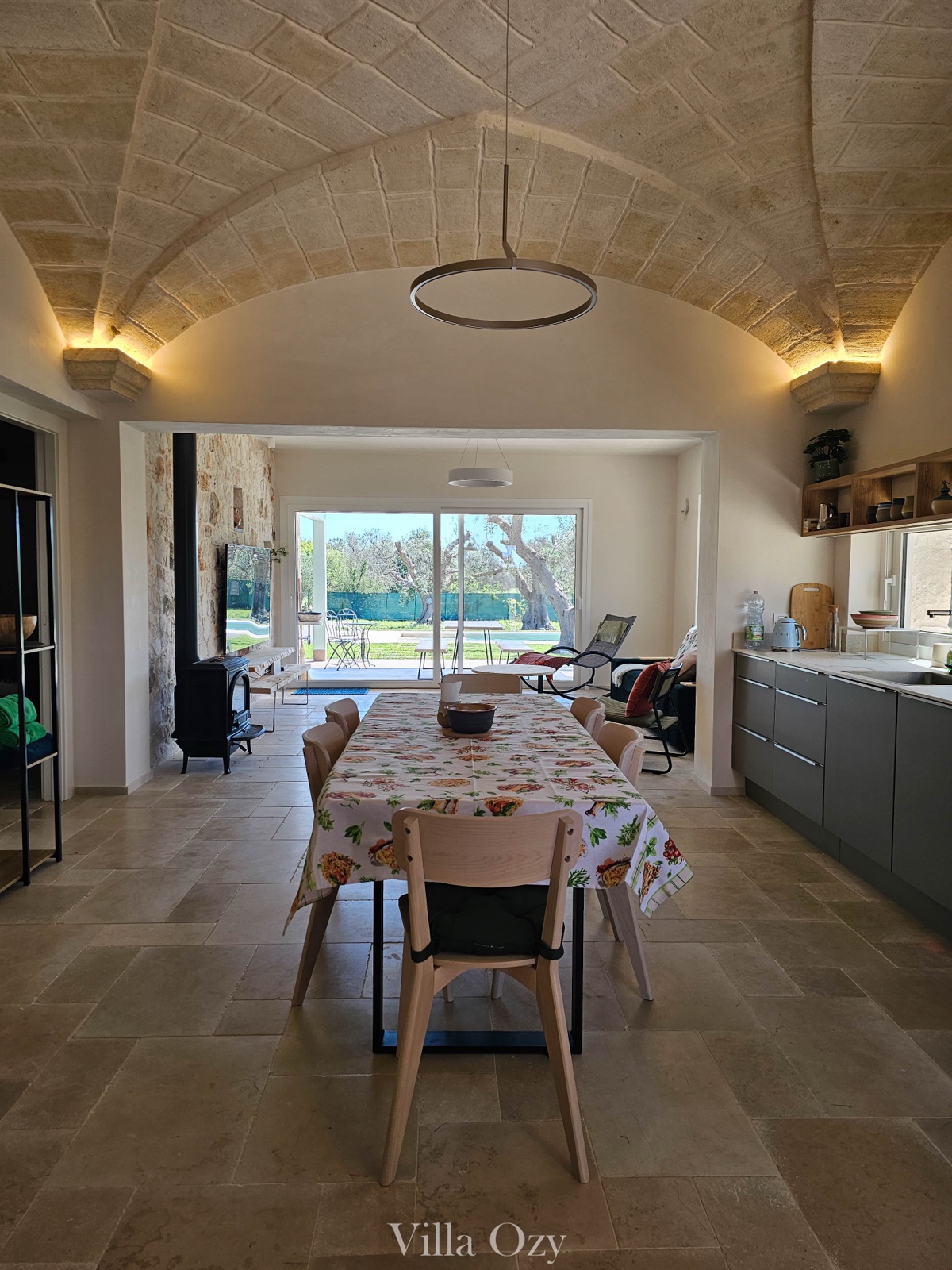 Stone-vaulted dining hall with long wooden table and open kitchen