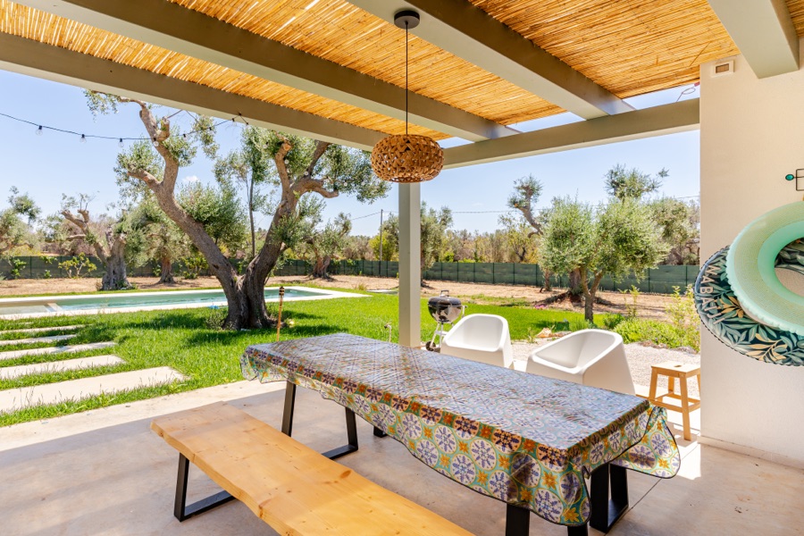 Bamboo pergola dining area with patterned tablecloth and a view of the pool