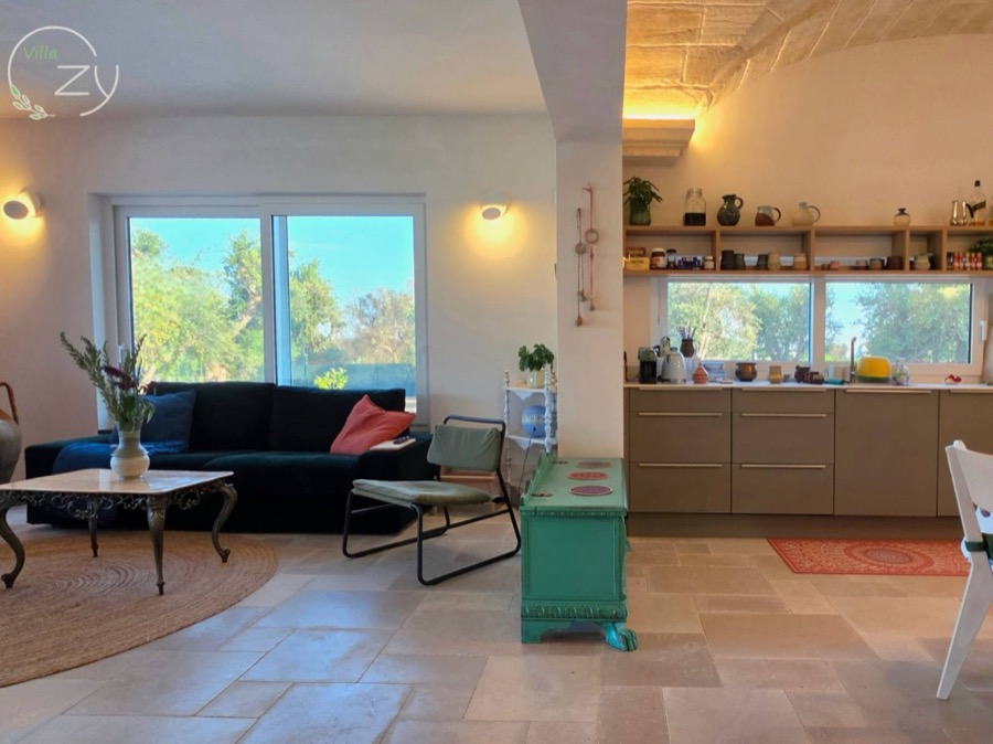 The sitting area beneath a stone vault, kitchen shelves lined with ceramics